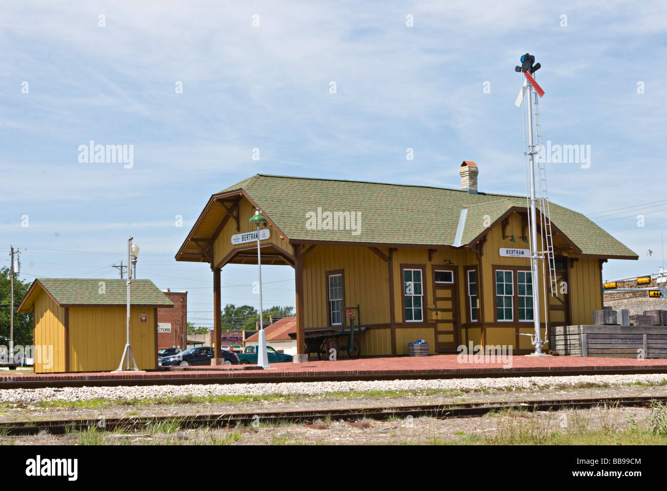 Small town railroad passenger train station with tracks, semaphore signal, mail catcher mail crane, passenger platform and outbuildings Stock Photo