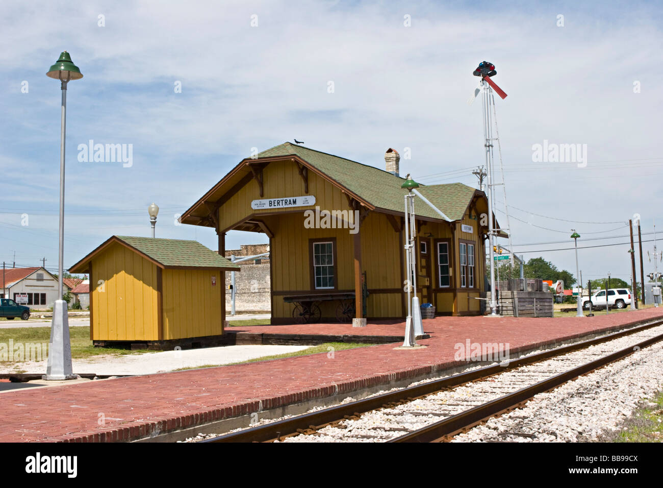 Small town railroad passenger train station with tracks, semaphore signal, mail catcher mail crane, passenger platform and outbuildings Stock Photo