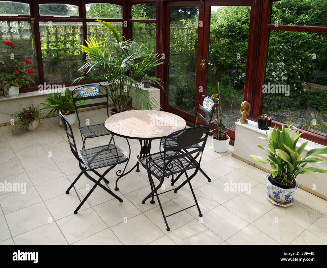 conservatory tables chairs plants room in house next to garden Stock