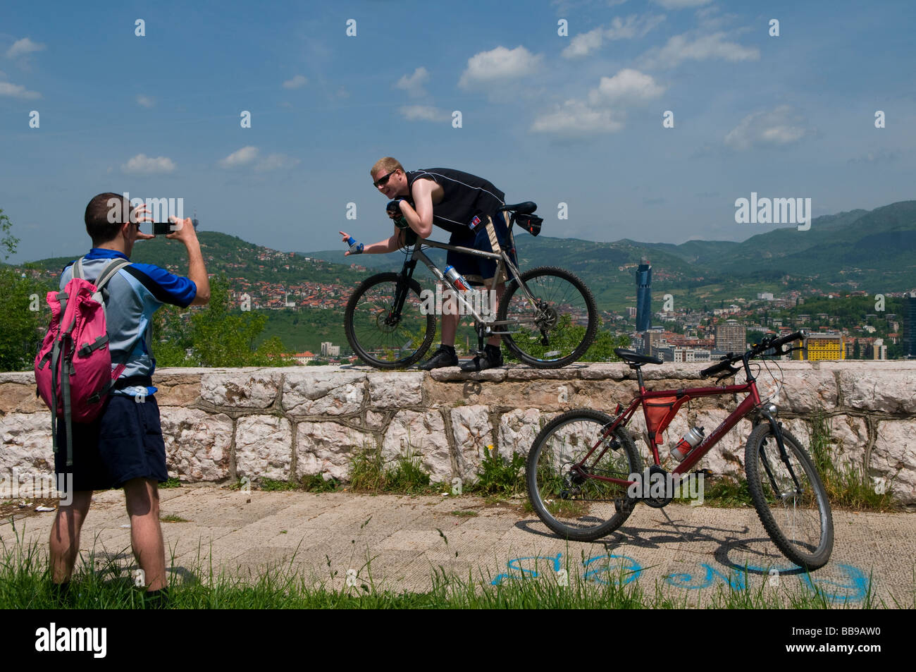 A cyclist photographs his friend at an observation point in a hill overlooking Sarajevo capital of  Bosnia Herzegovina Stock Photo
