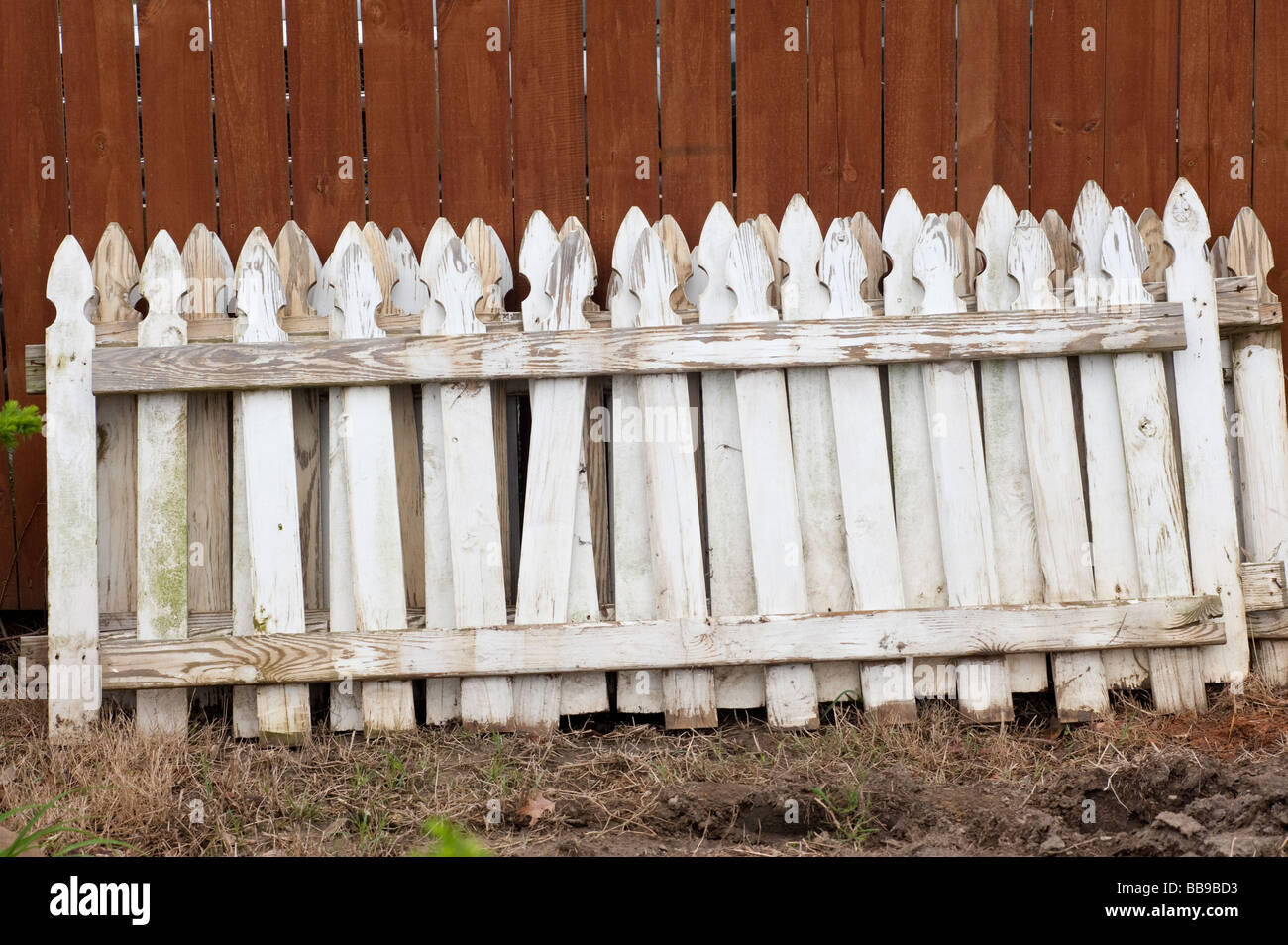 fence railing stacks against a red fence Stock Photo