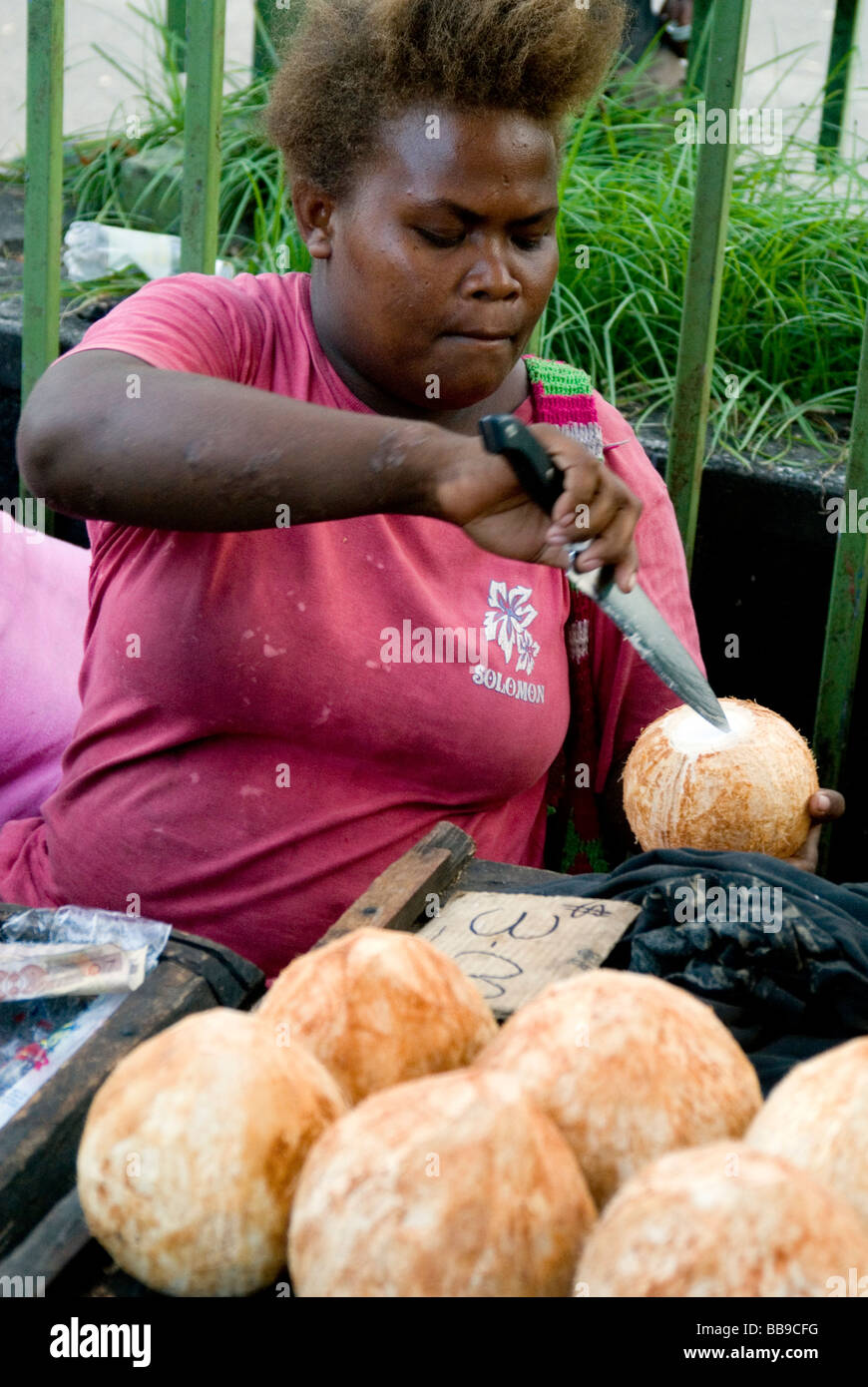 Market vendor opening coconuts in Honiara, Solomon Islands Stock Photo