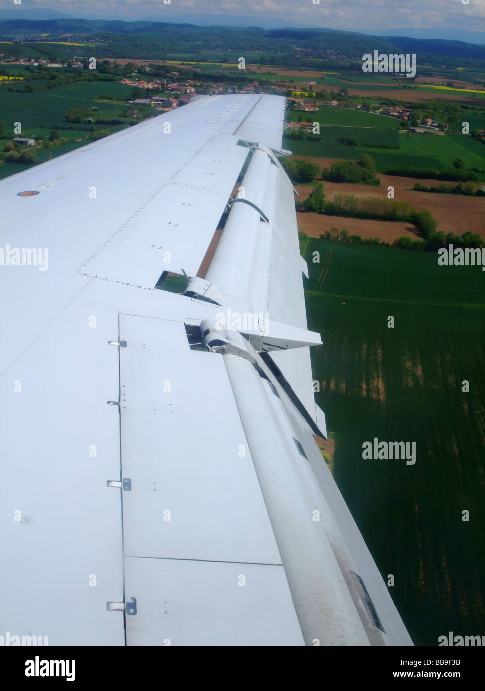 Embraer ERJ-145  aircraft wing with split flaps (model Fowler) down during the final step on landing. Stock Photo