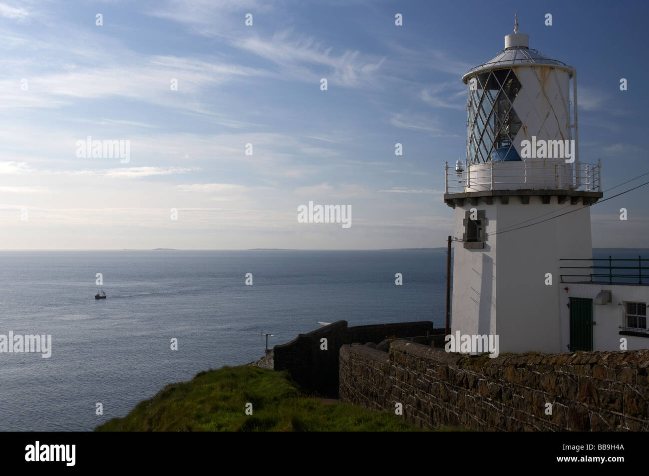 blackhead whitehead lighthouse on cliff face overlooking the sea with small fishing boat far below county antrim Stock Photo