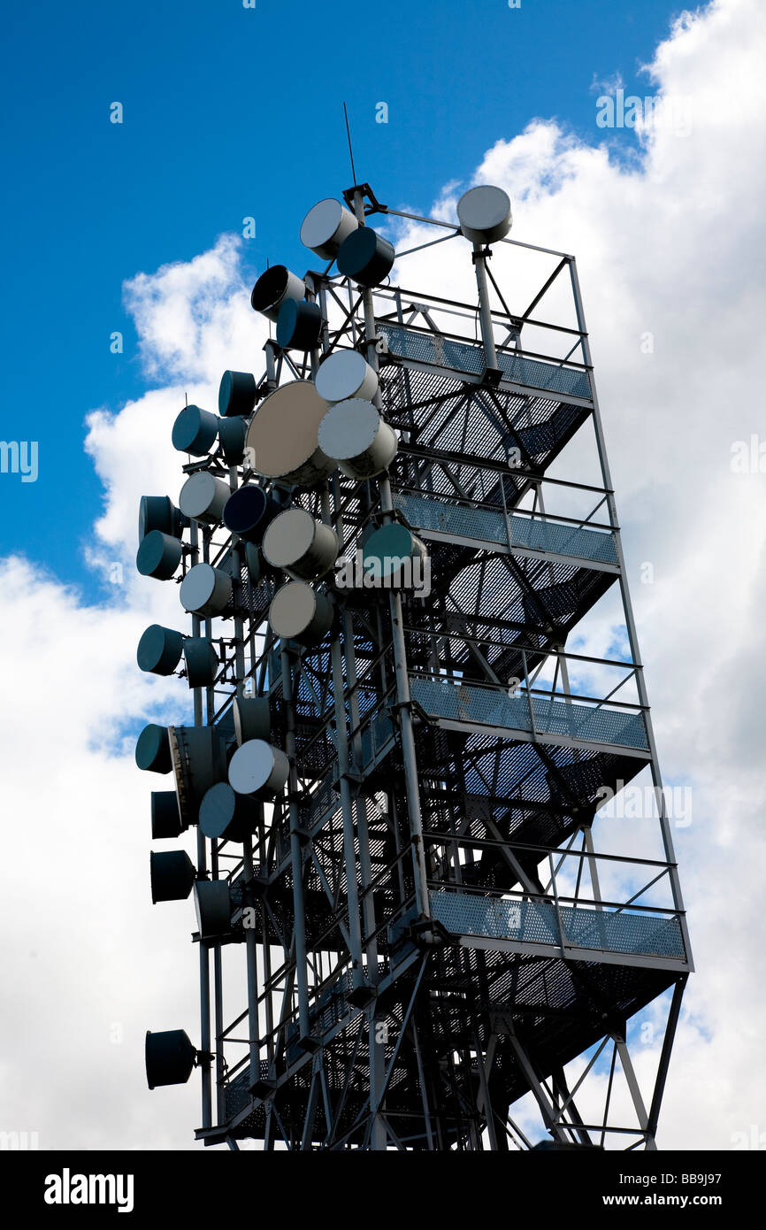 A communication tower, covered in various ariels and dishes, behind a fence in the North of England, UK. Blue sky with clouds. Stock Photo