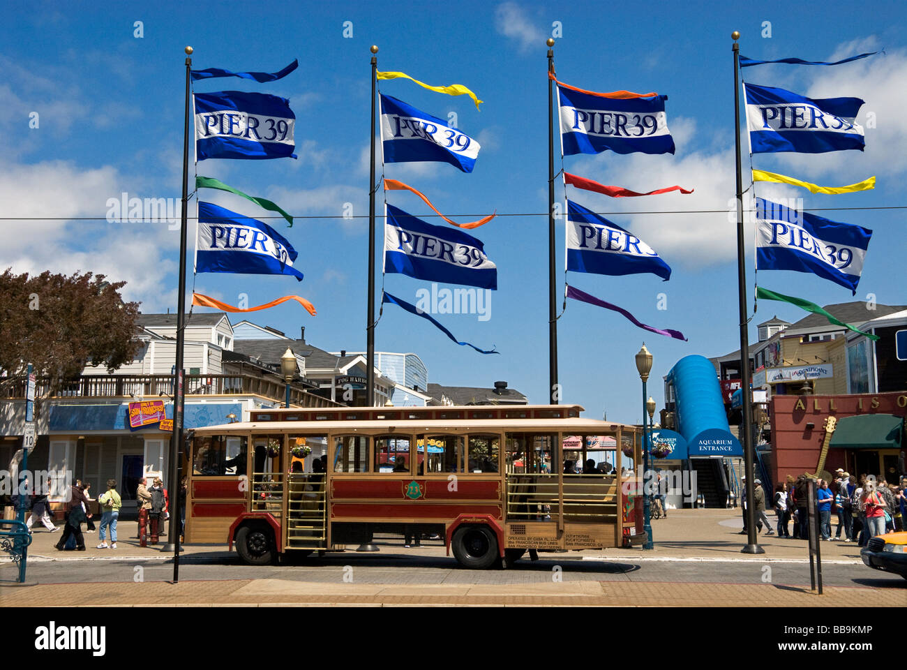 Flags waving at Pier 39 with trolley bus in foreground is a major tourist attraction in San Francisco California USA Stock Photo