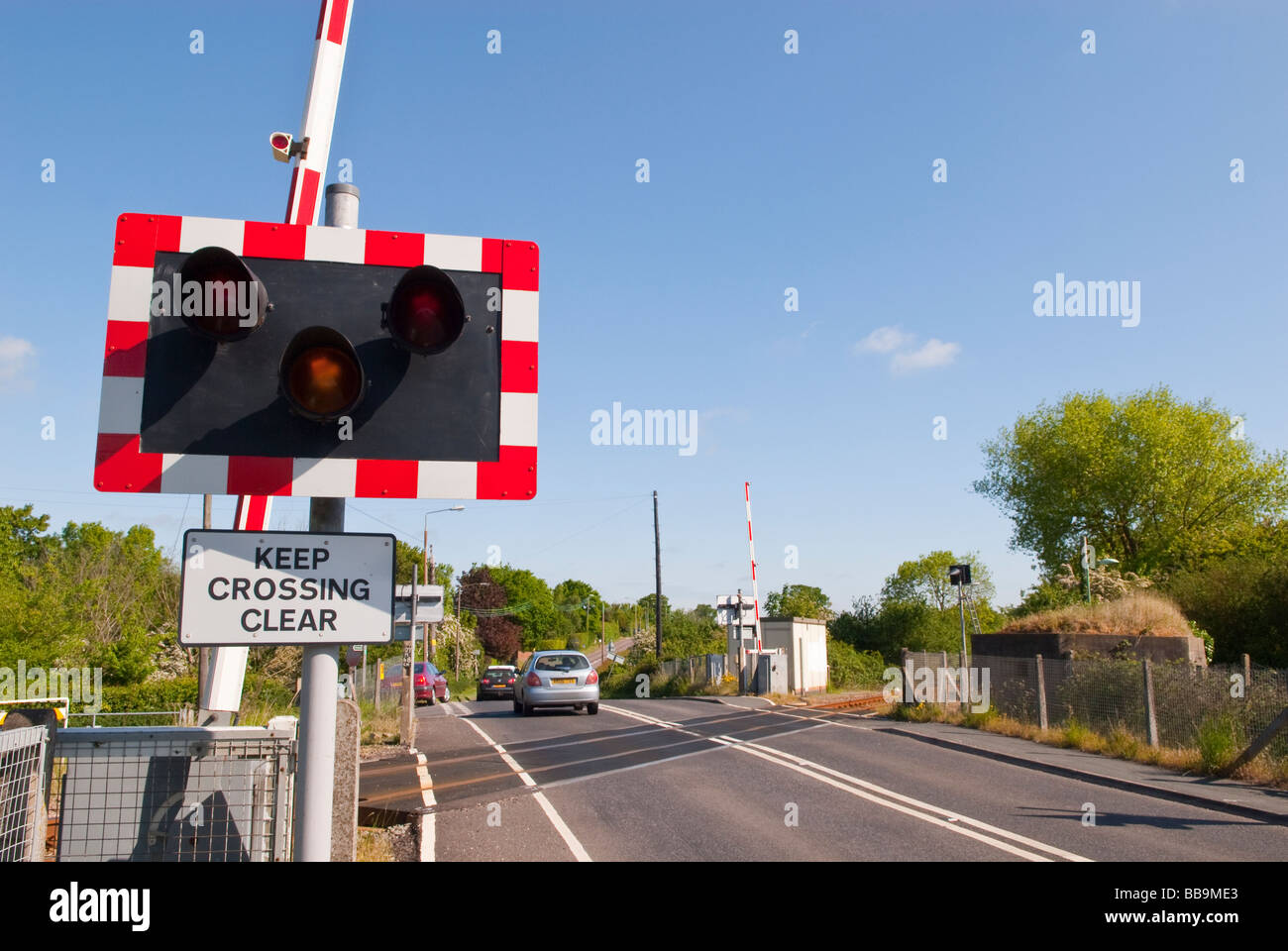 An automatic  barrier with warning lights on a uk railway train track crossing the road with sign reading keep crossing clear Stock Photo