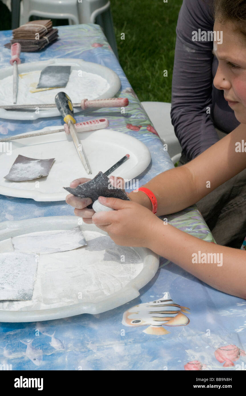 Child polishing a pebble at an outdoor hand craft fair Stock Photo