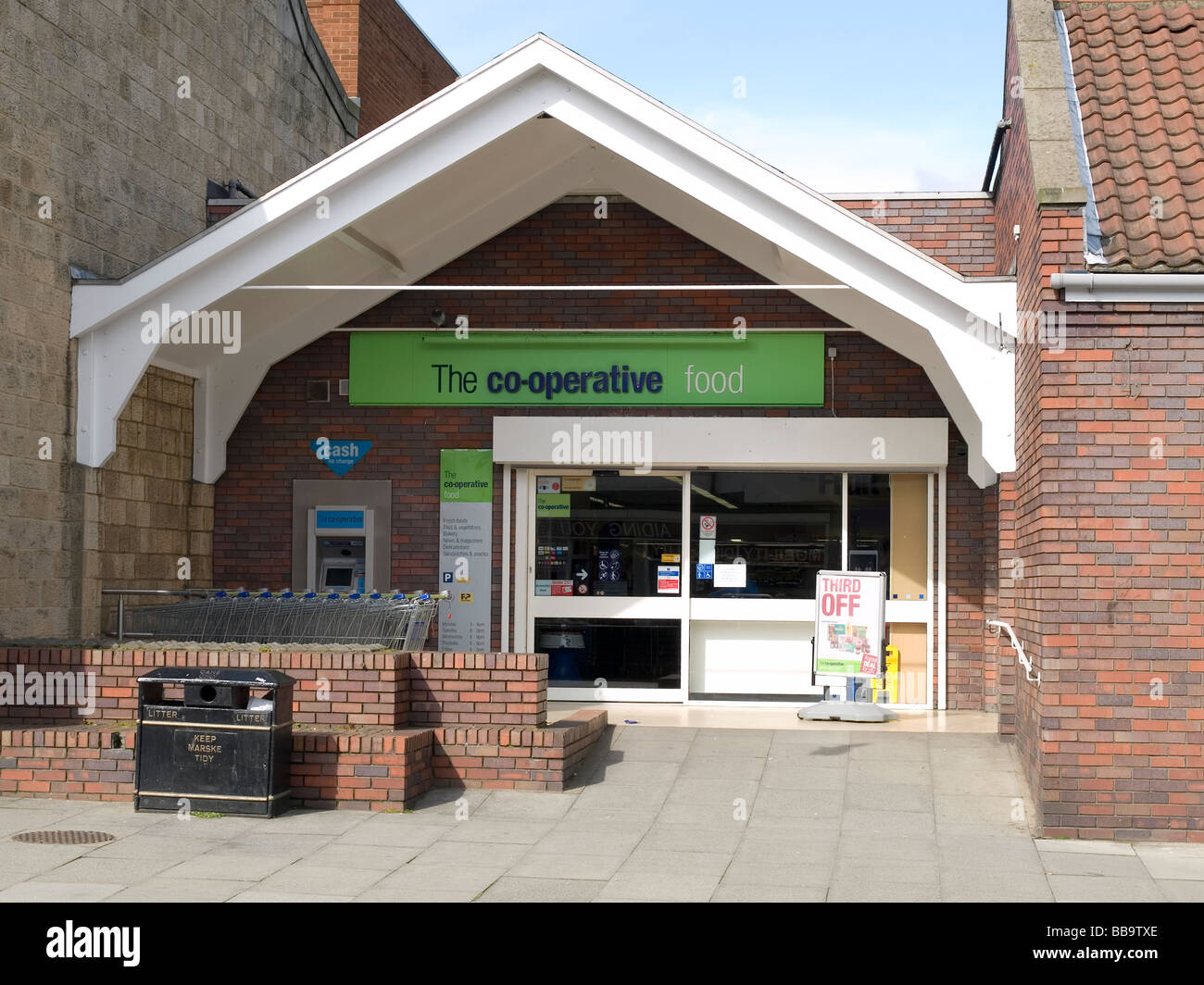 Entrance to a co operative supermarket with trolleys and a cash machine Stock Photo