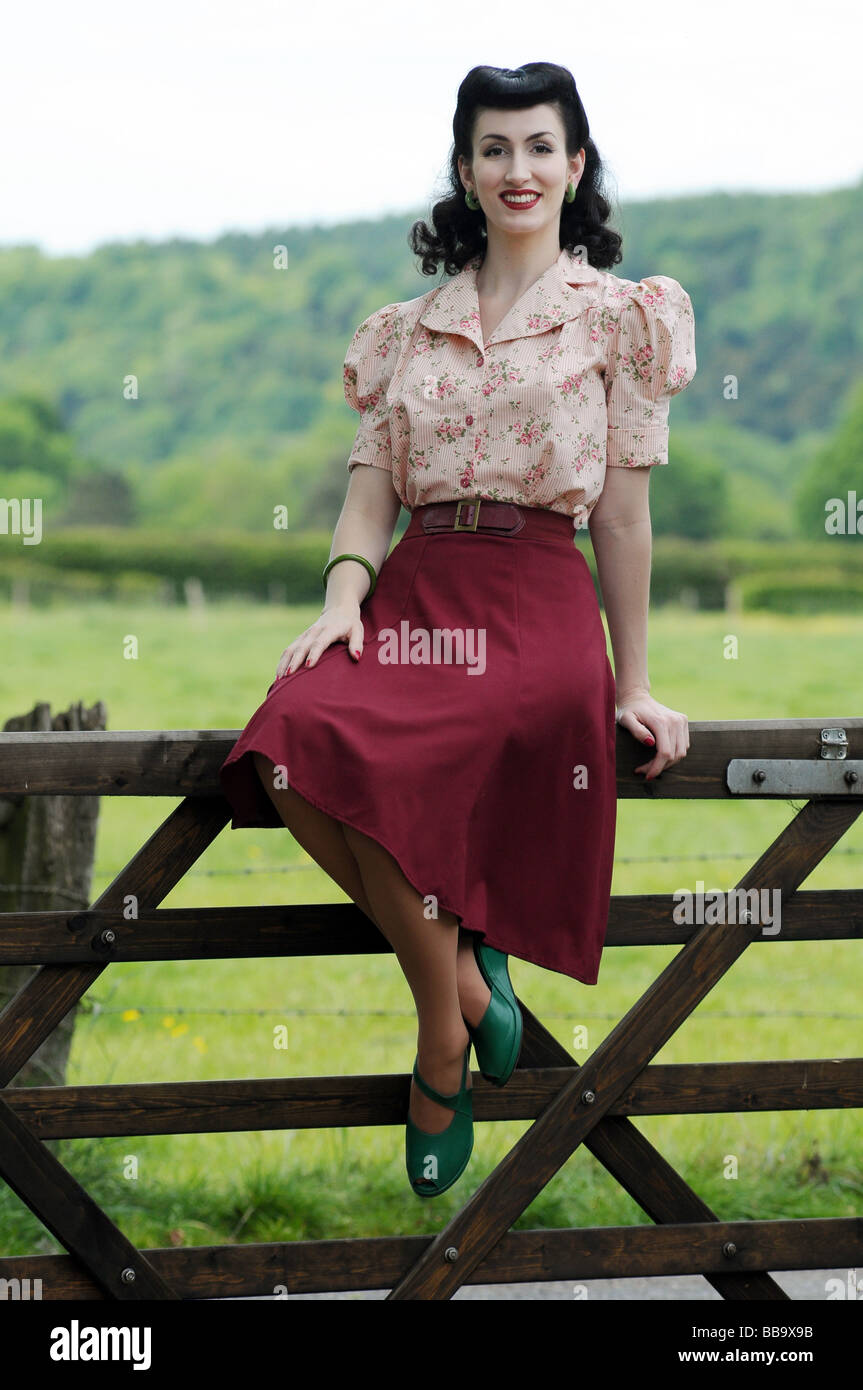 Woman in old fashioned clothing sitting on gate Stock Photo - Alamy