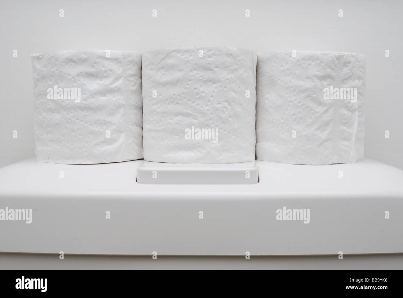 Three spare rolls of toilet paper on toilet cistern Stock Photo