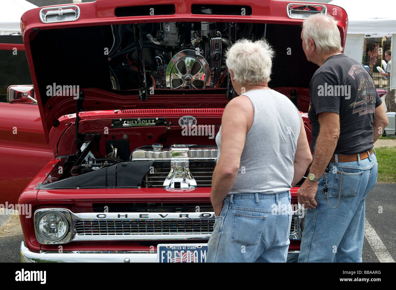 antique red chevy pickup truck with 2 men looking at engine Stock Photo