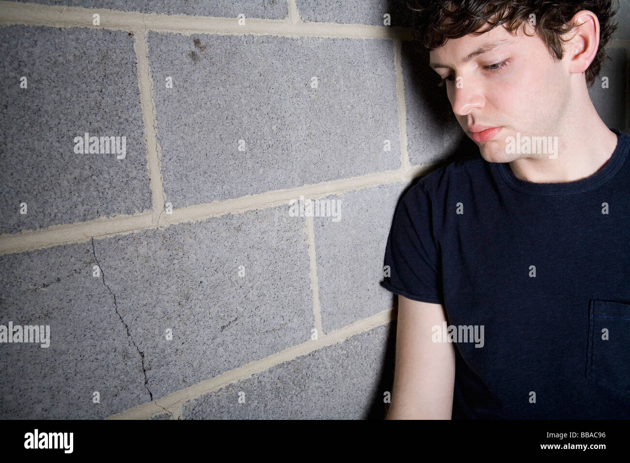 A young man leaning against a brick wall Stock Photo - Alamy