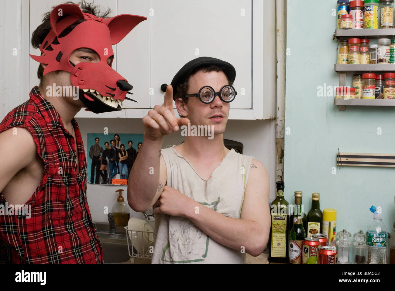 Two young men standing in a kitchen wearing silly disguises Stock Photo