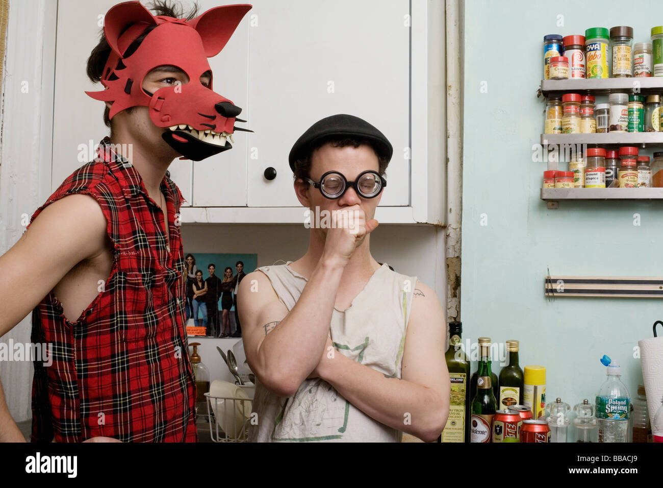 Two young men standing in a kitchen wearing silly disguises Stock Photo