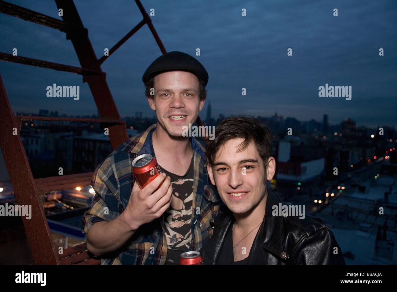 Two young men standing on a fire escape at night Stock Photo
