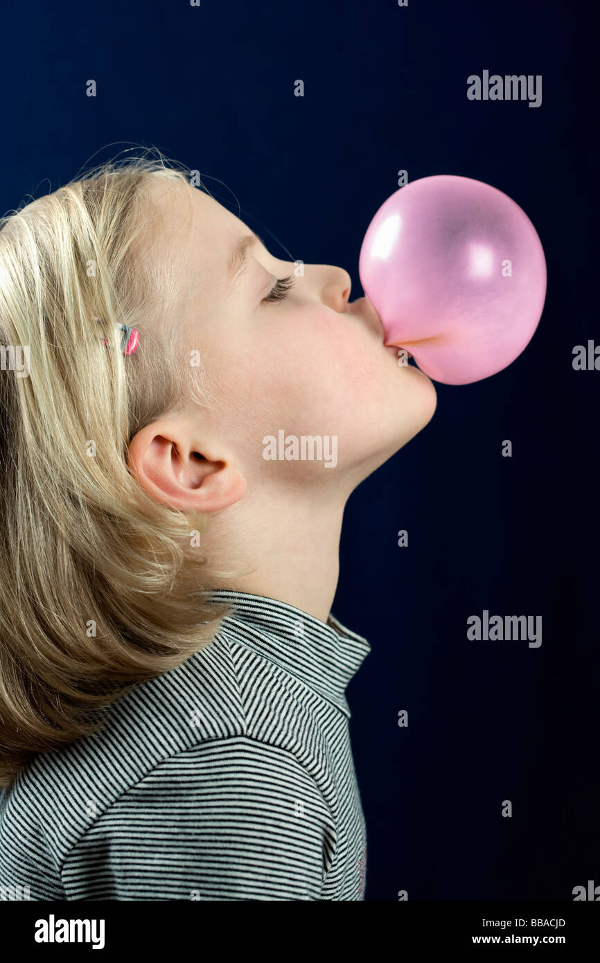 A young girl blowing a chewing gum bubble Stock Photo
