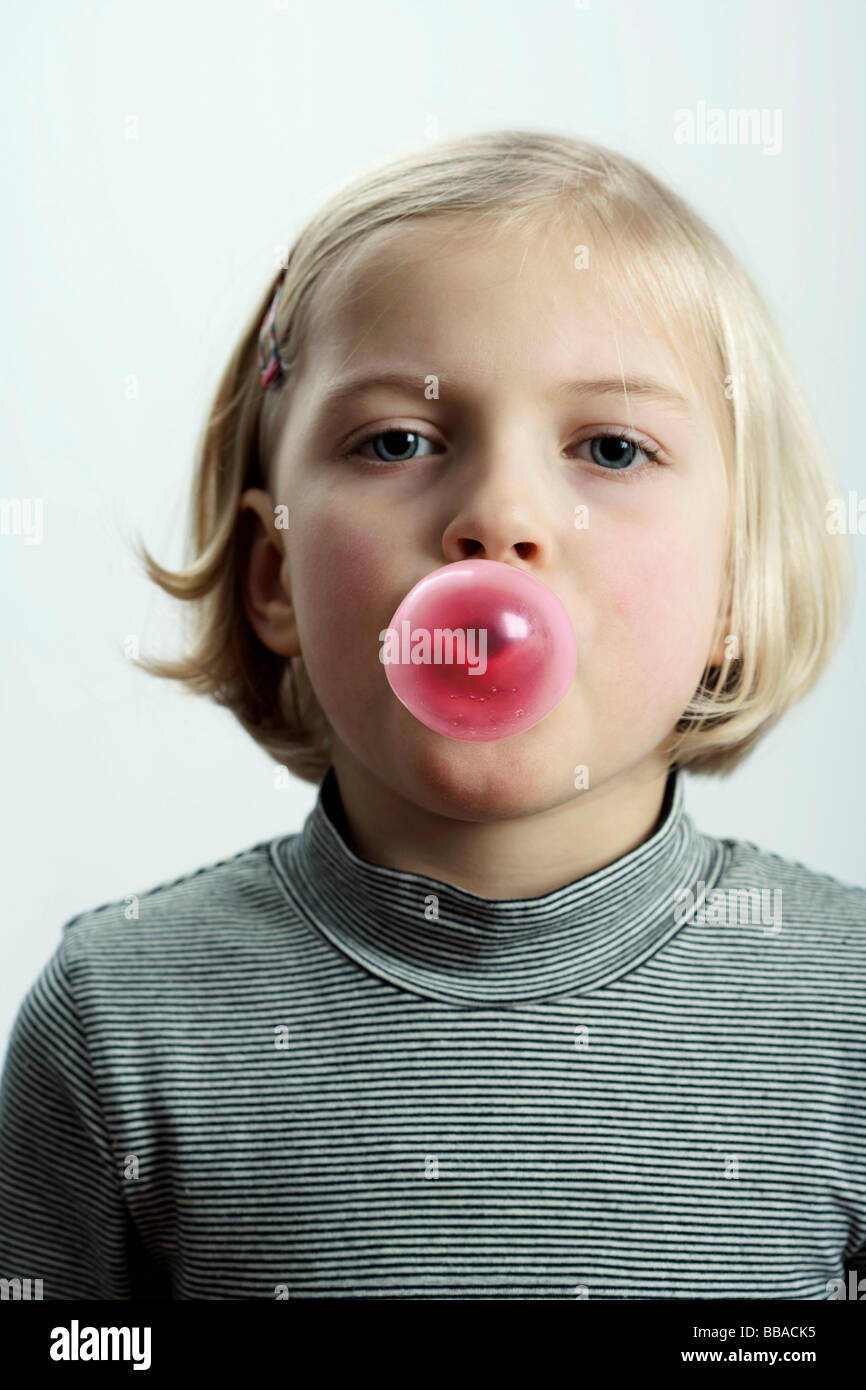 A young girl blowing a chewing gum bubble Stock Photo