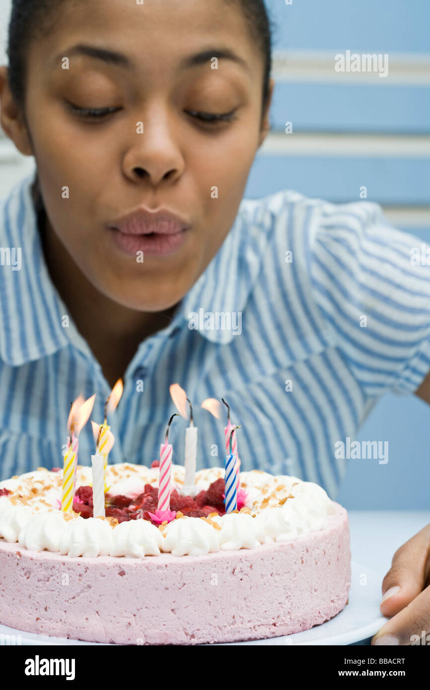 A young woman blowing out candles on a birthday cake Stock Photo Alamy