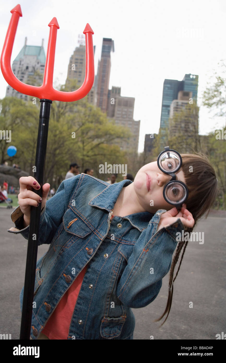 A young girl wearing funny glasses and holding a devil's pitchfork Stock Photo