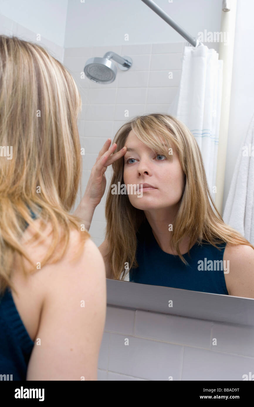 A young woman looking in a bathroom mirror Stock Photo Alamy