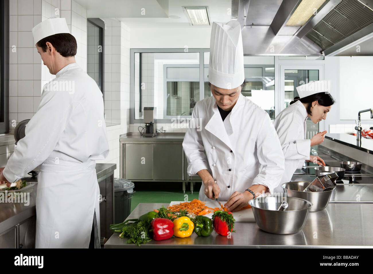 Three chefs working in a commercial kitchen Stock Photo