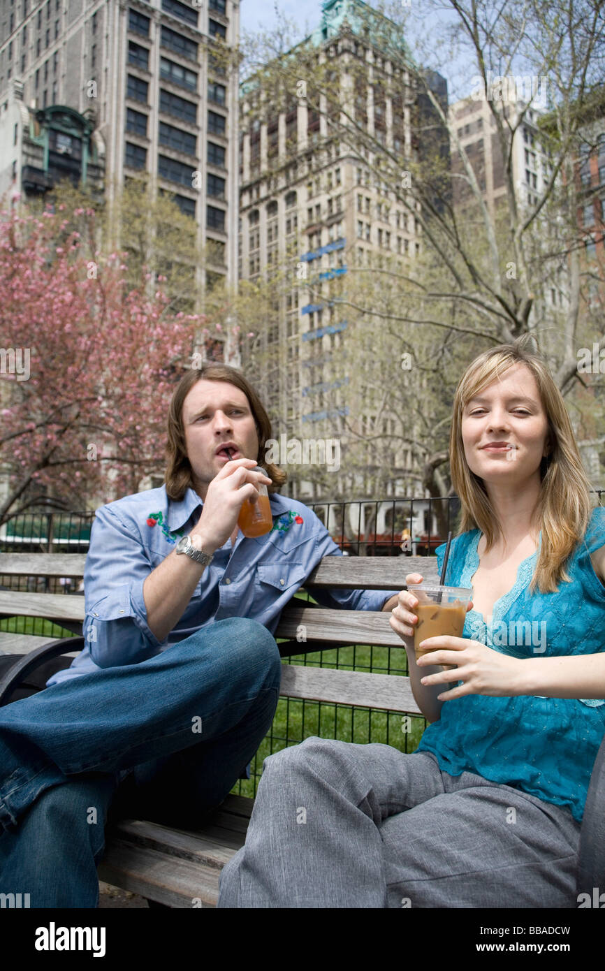 A young couple sitting on a park bench with iced coffees, Central Park, New York City Stock Photo