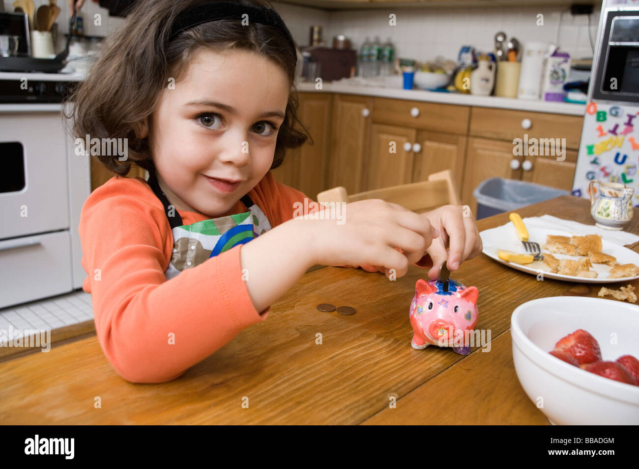 A young girl putting coins into a piggy bank Stock Photo - Alamy