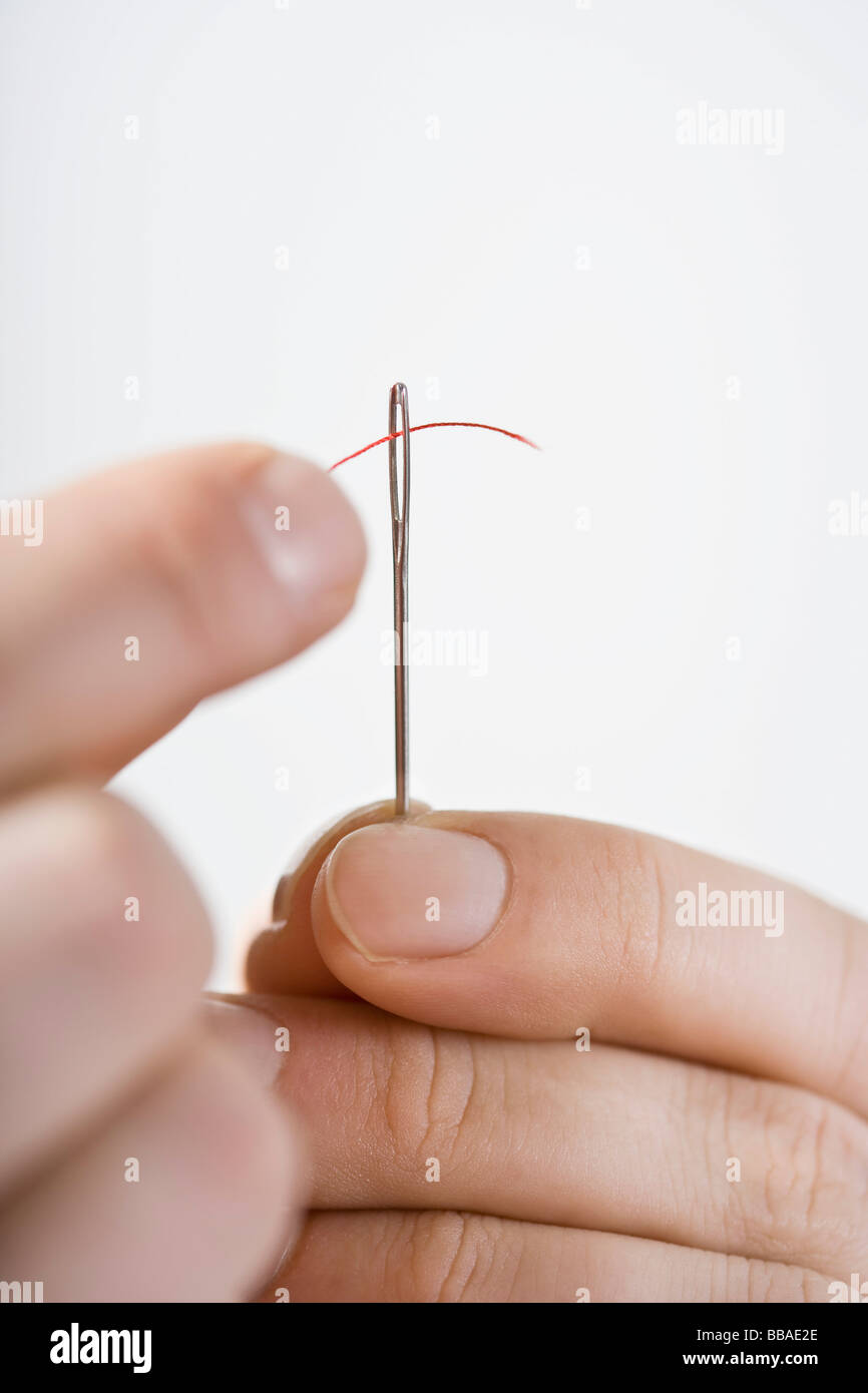 A man threading a needle Stock Photo Alamy