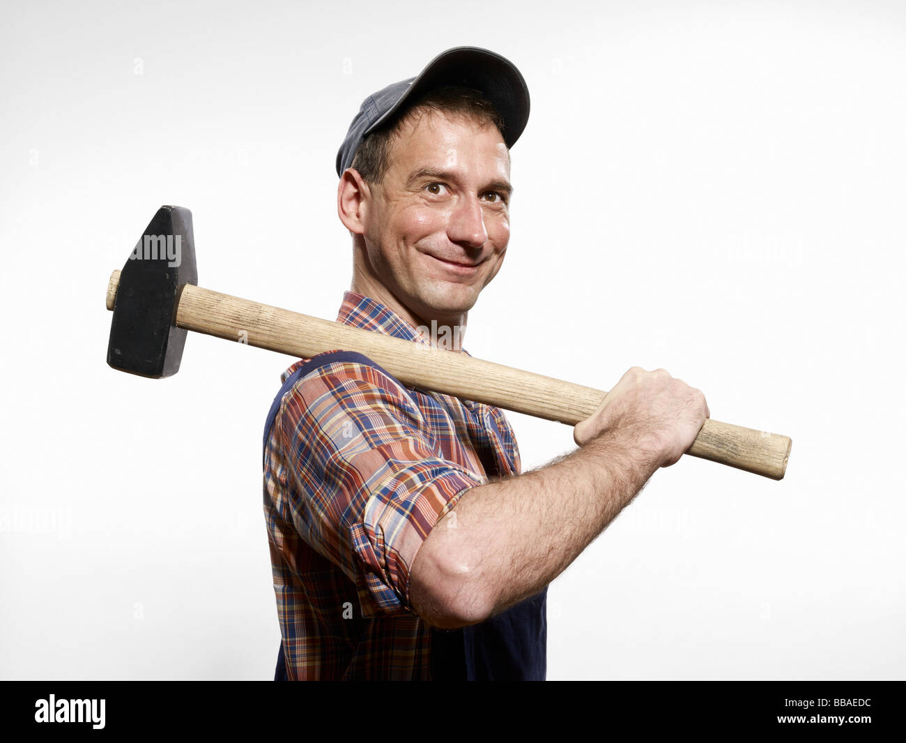 A man holding a sledgehammer over his shoulder Stock Photo - Alamy