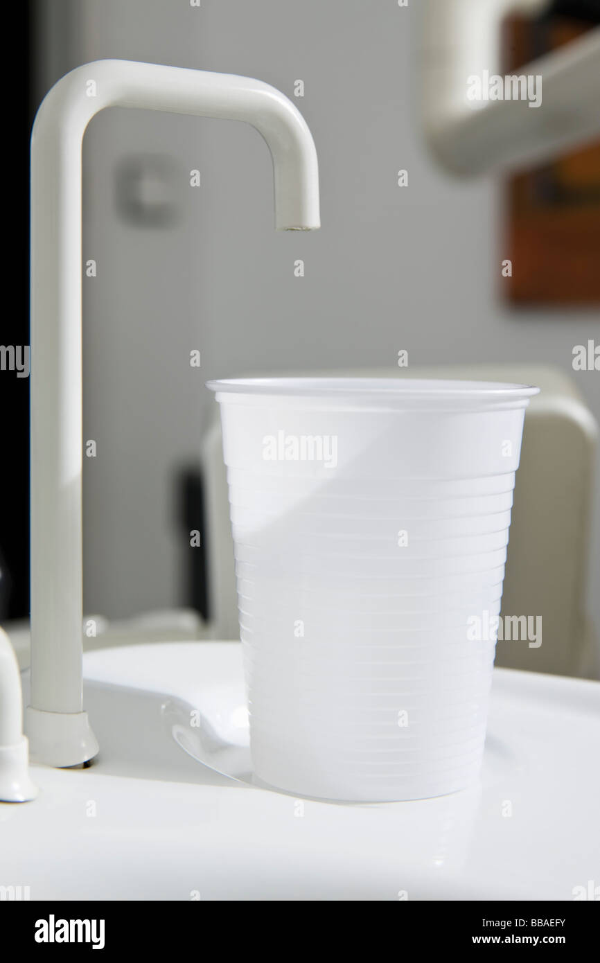 A plastic cup at the edge of a dental cuspidor Stock Photo