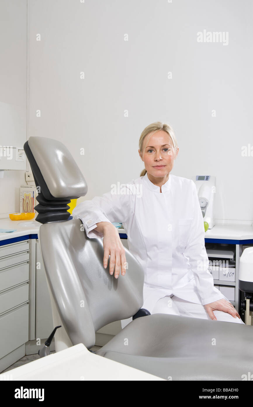 Portrait of a dental assistant sitting behind a dental chair Stock Photo