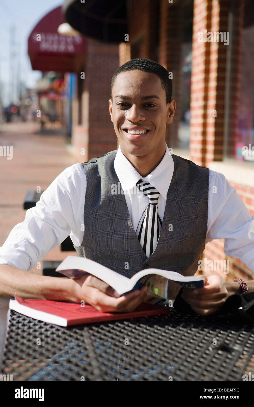 A young man sitting at a pavement cafe and reading books Stock Photo