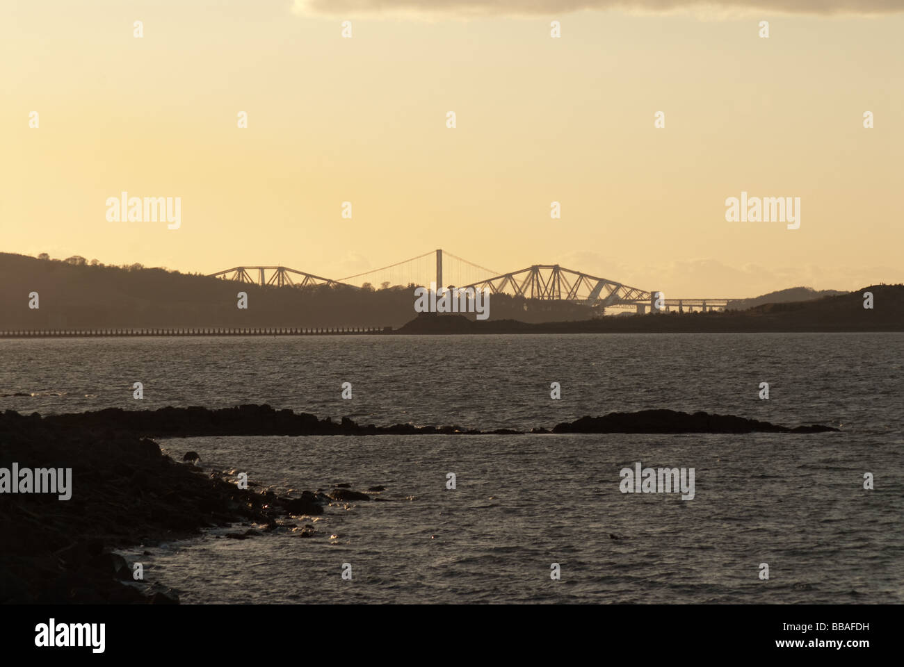 Forth road and rail bridge at dusk from Granton Harbour, Leith, Edinbugh, Scotland with rocks in the foreground Stock Photo