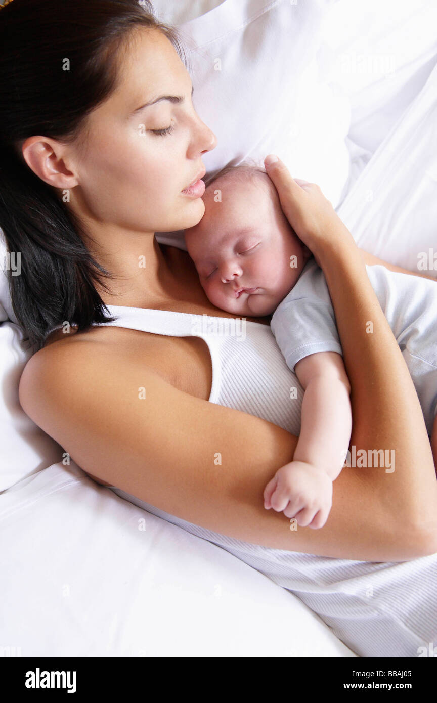 Woman and her baby sleeping in bed Stock Photo