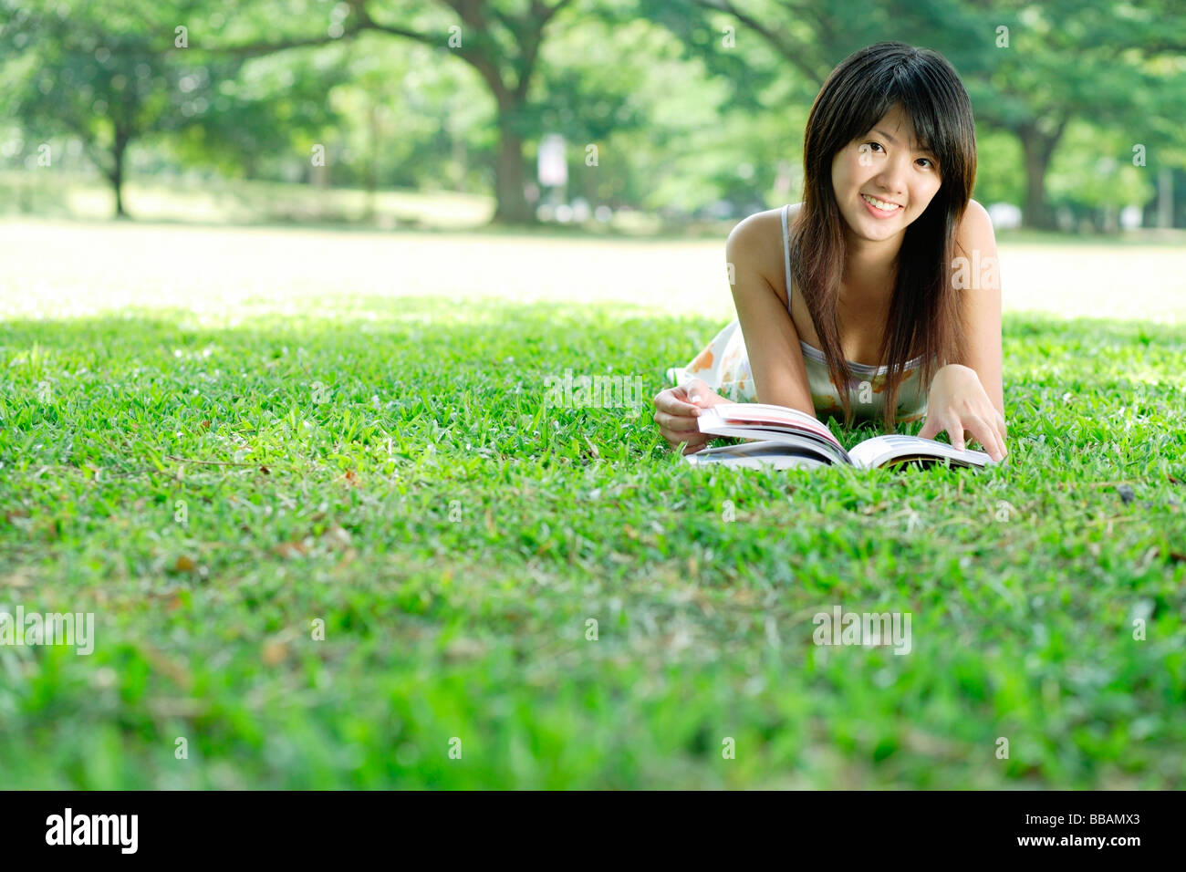 Young woman lying on grass in park, looking at camera Stock Photo - Alamy