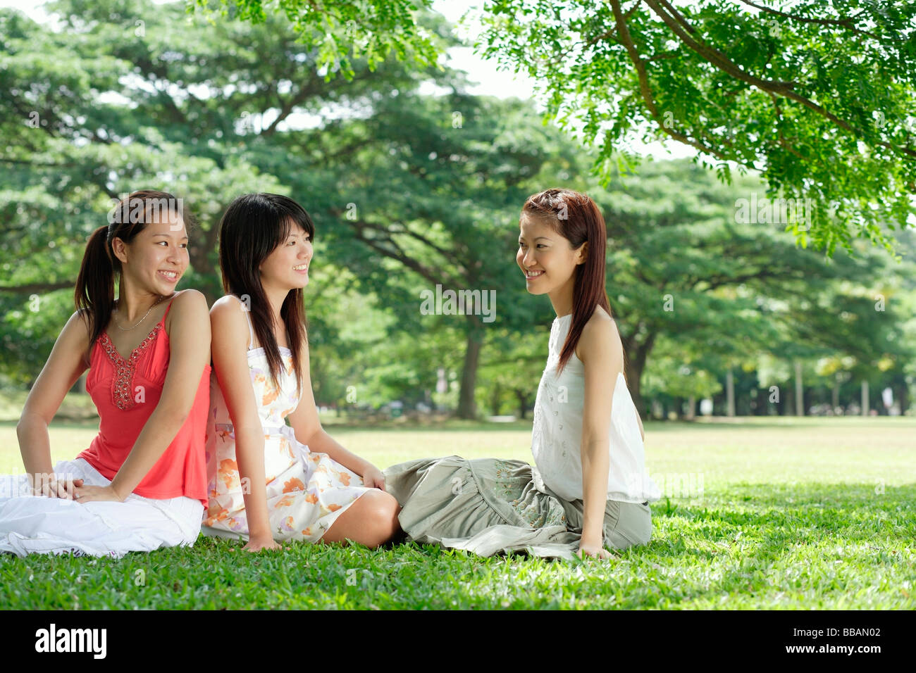 Young women in park, sitting on grass Stock Photo - Alamy