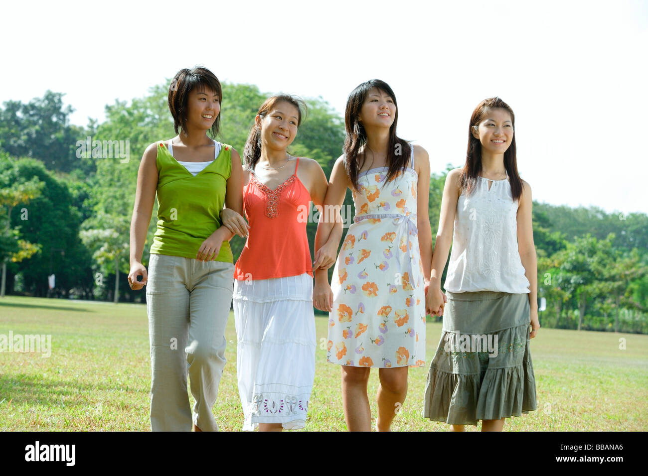Young women walking side by side in park Stock Photo - Alamy