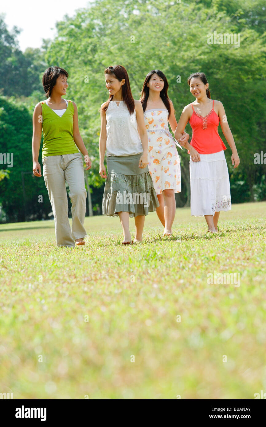 Four young women walking side by side in park Stock Photo - Alamy