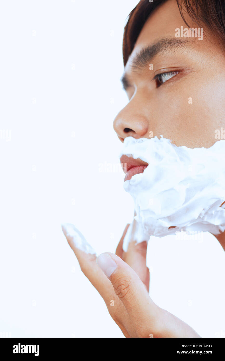 Young man with shaving foam on face, sideview Stock Photo Alamy