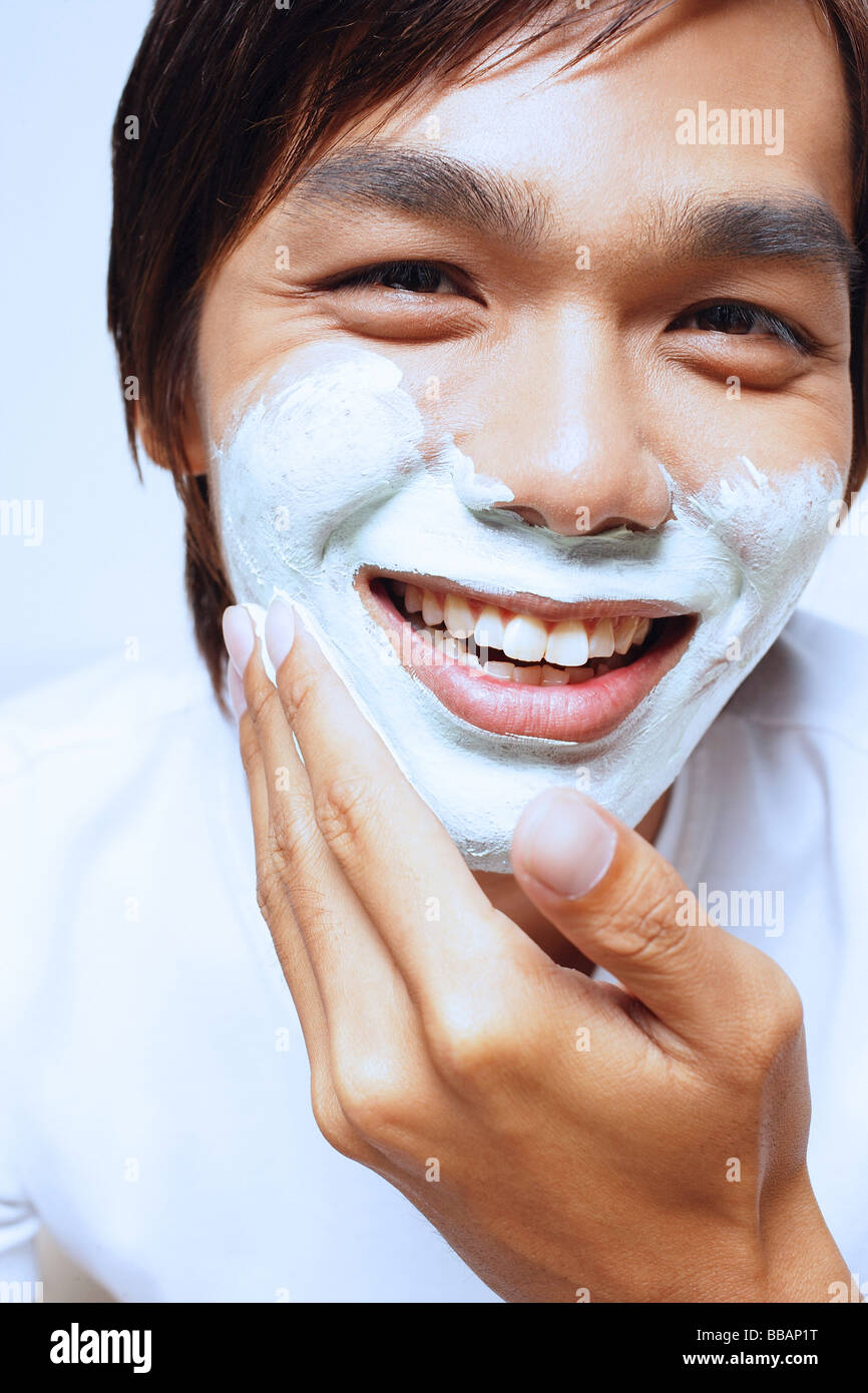 Young man applying shaving foam on face Stock Photo Alamy
