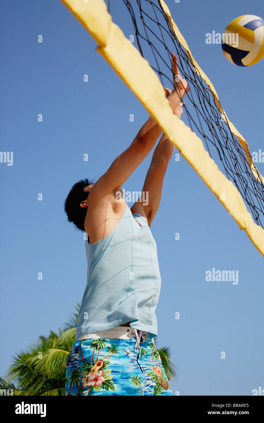 Guy playing volleyball, hitting ball over net Stock Photo Alamy