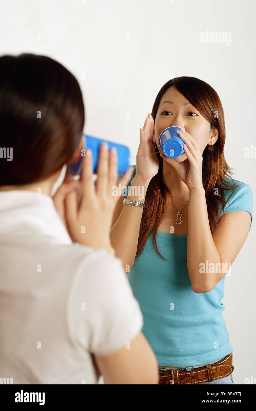 Two women talking using paper cup phone Stock Photo - Alamy