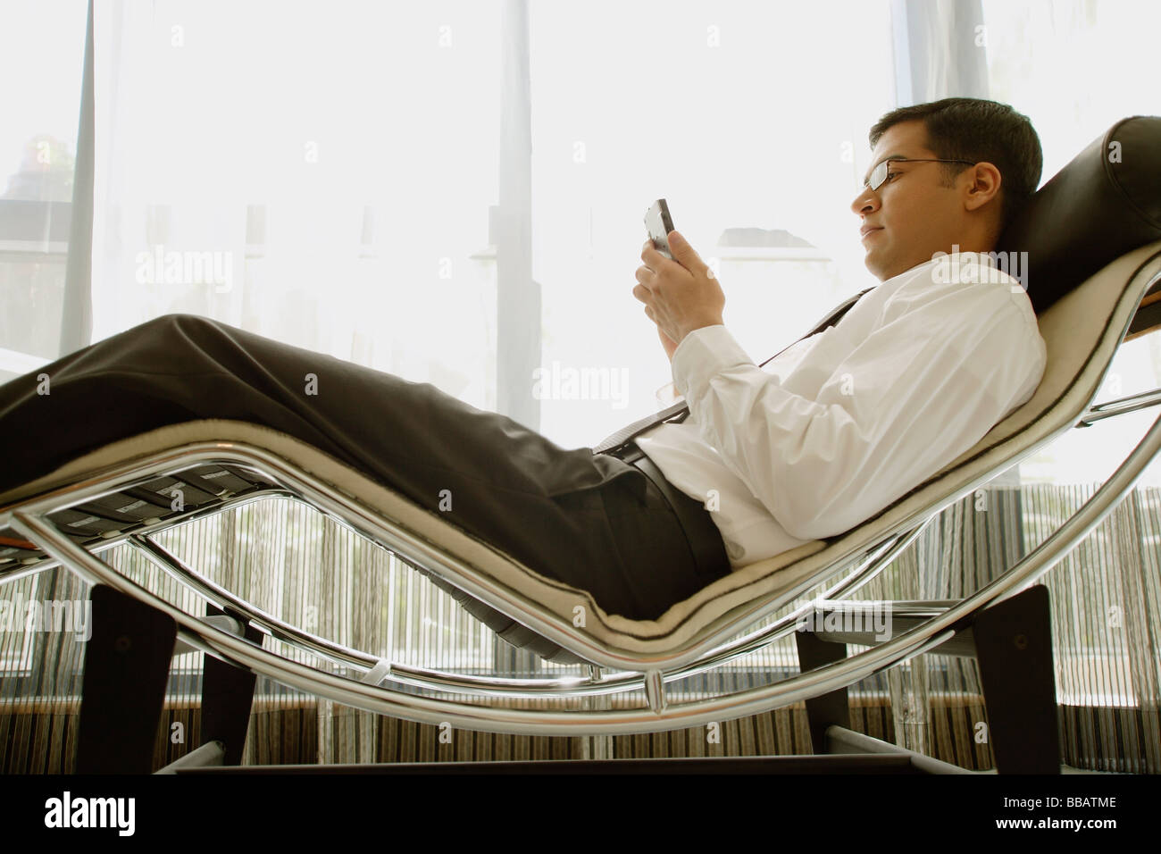 Businessman reclining on chair, using PDA Stock Photo Alamy