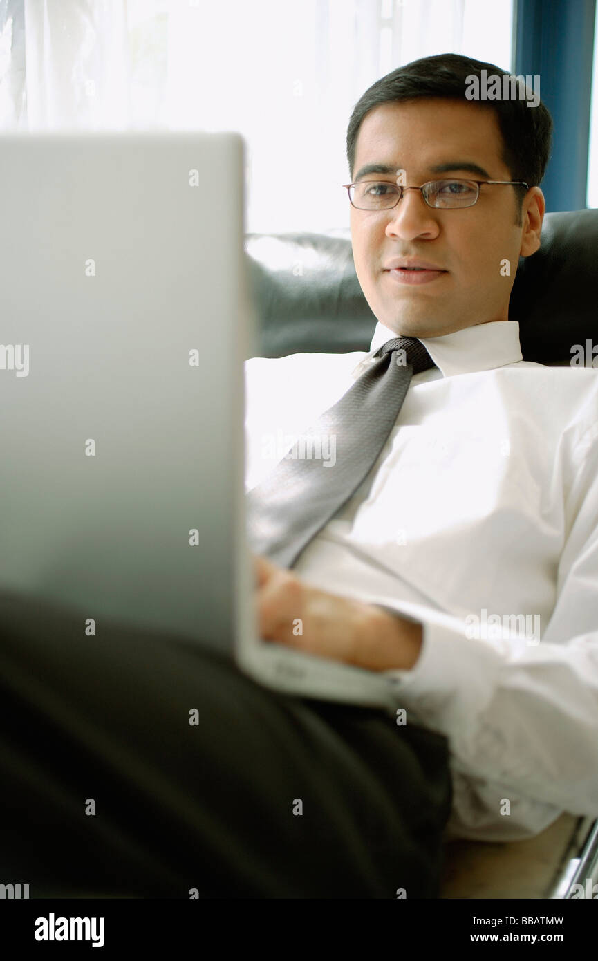 Businessman reclining on chair with laptop Stock Photo Alamy
