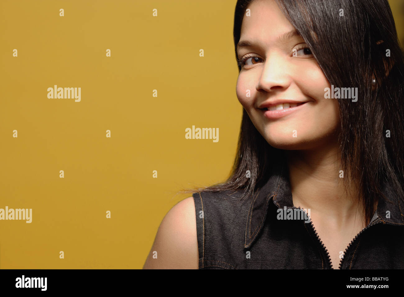 Young woman against yellow background, looking at camera, portrait ...
