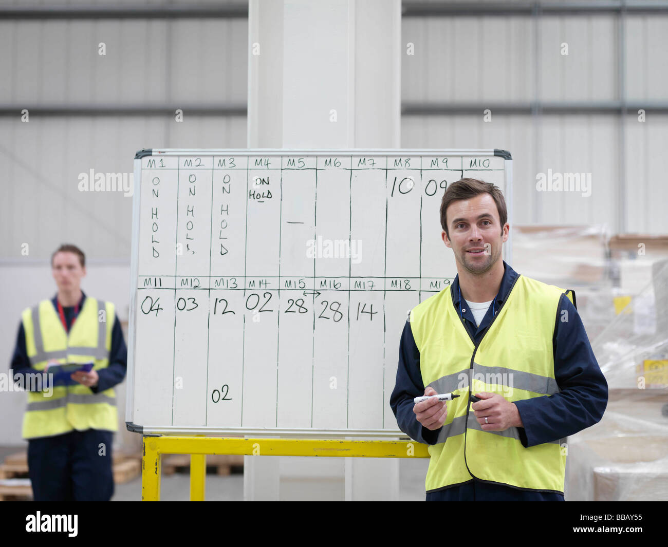 Workers With Whiteboard In Warehouse Stock Photo
