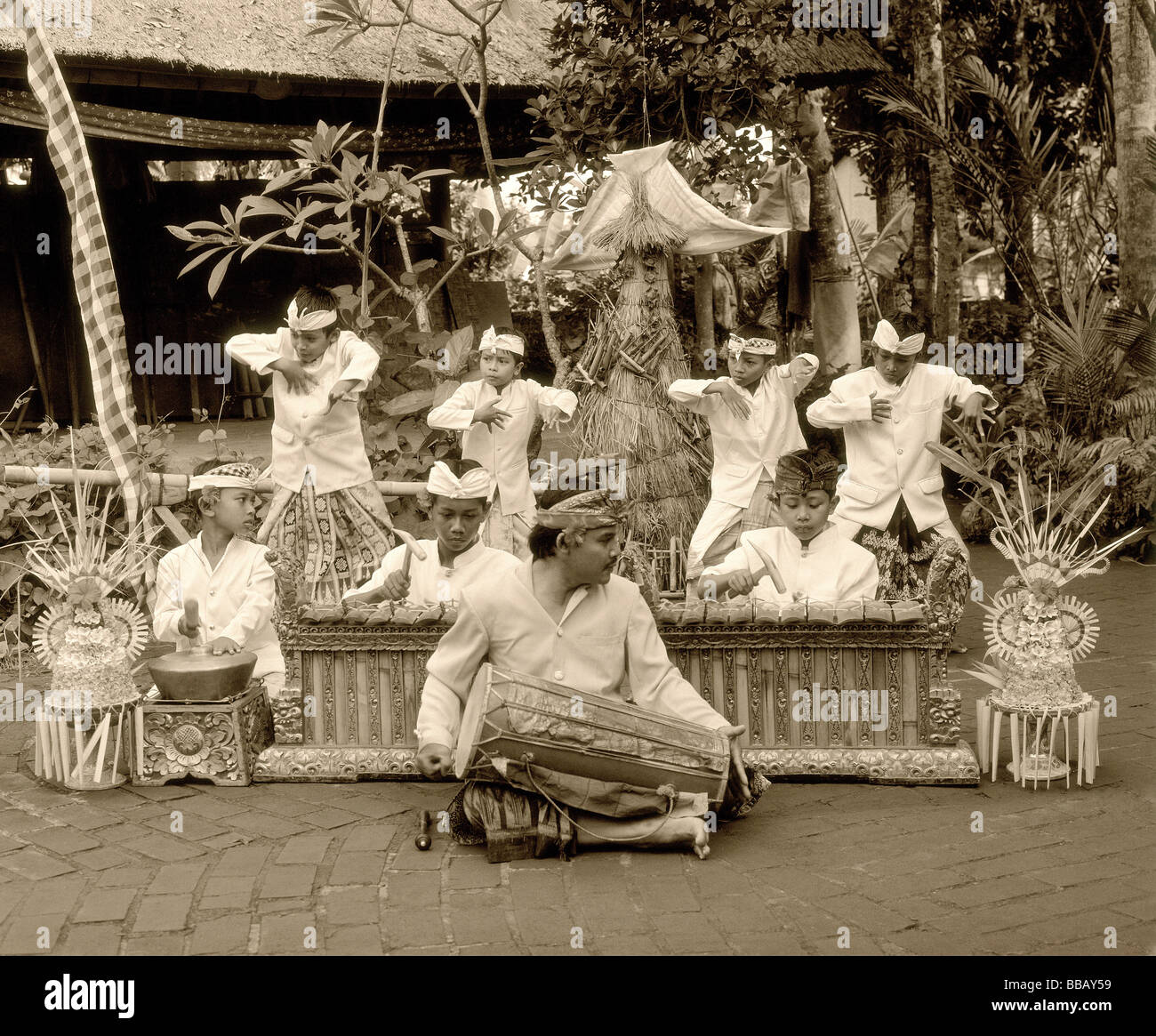 Indonesia, Bali, man playing hand drum, young boy dancers in traditional costume Stock Photo