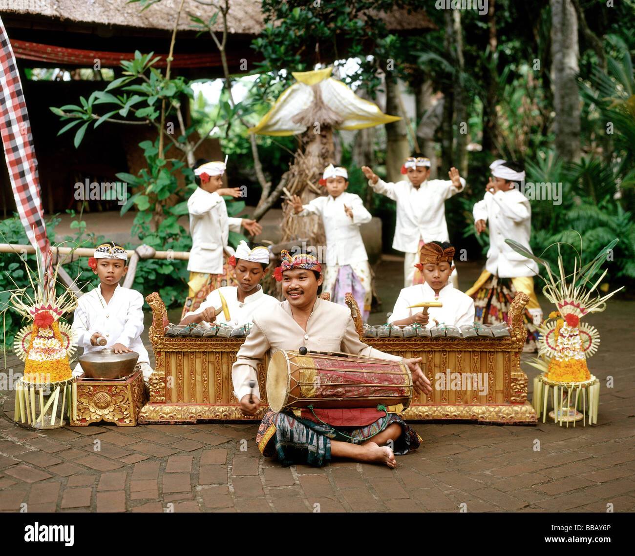 Indonesia, Bali, man playing hand drum, young boys in traditional costume dancing Stock Photo