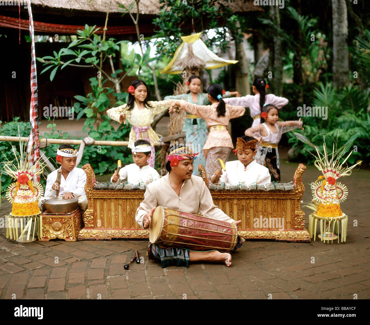 Indonesia, Bali, man playing hand drum, boys playing instruments and girls  dancing in background in traditional costume Stock Photo - Alamy